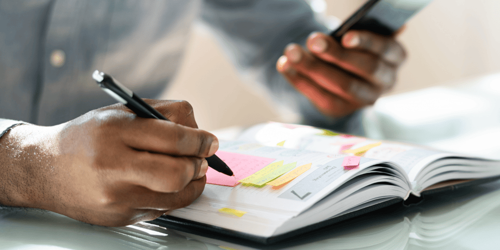 Stock Image of Man Writing in a Planner to Schedule a Home Renovation in Gainesville