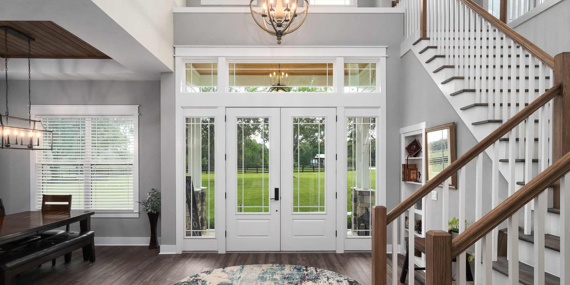 Entryway of a whole home remodel with French doors, built-in storage, and a staircase by Robinson Renovation & Custom Homes in Gainesville, FL