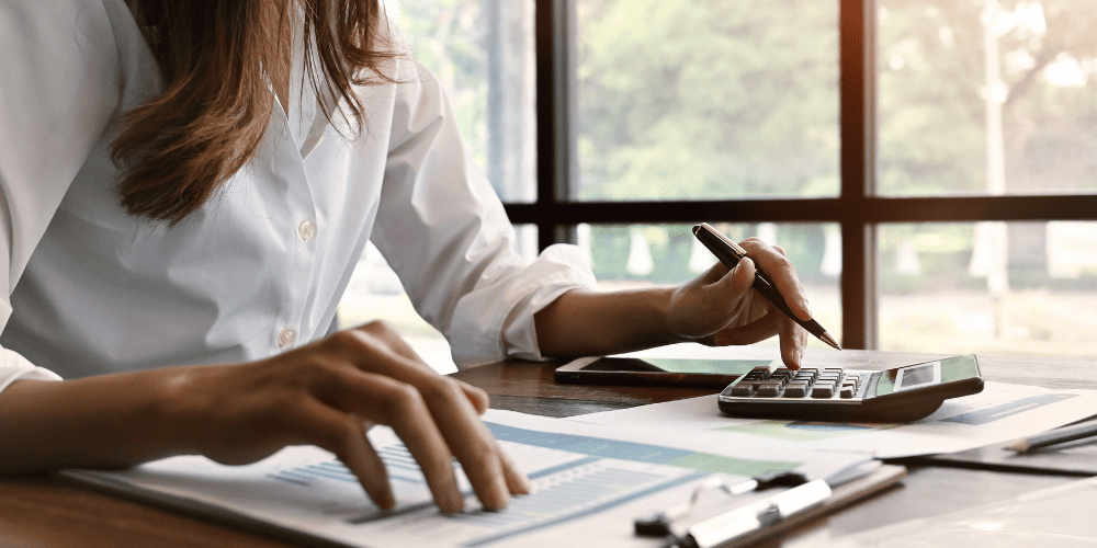 Stock Image of Woman Filling Out Forms with a Calculator