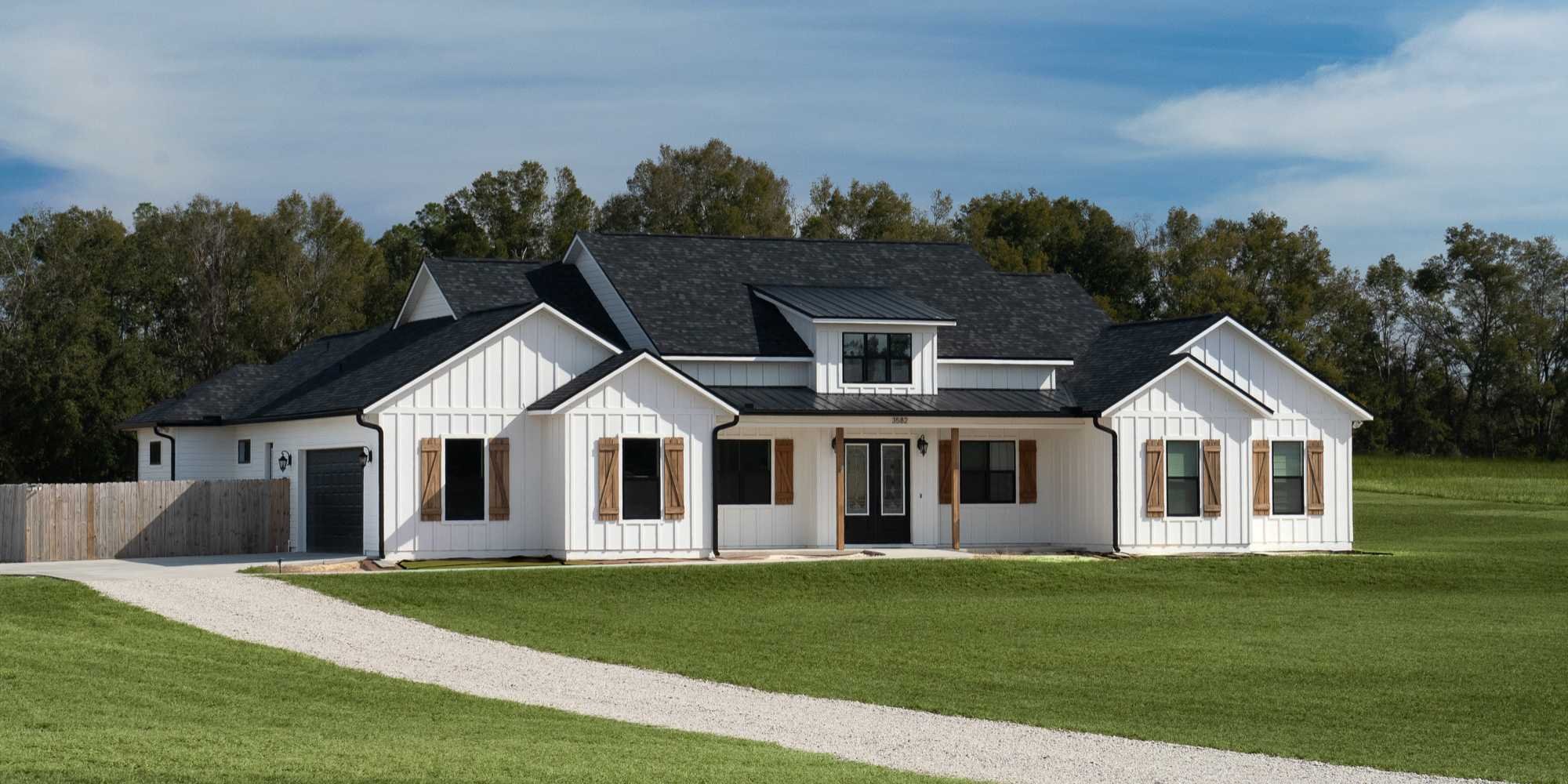 custom white farmhouse in Gainesville, FL with black roof and wood shutters by Robinson Renovation