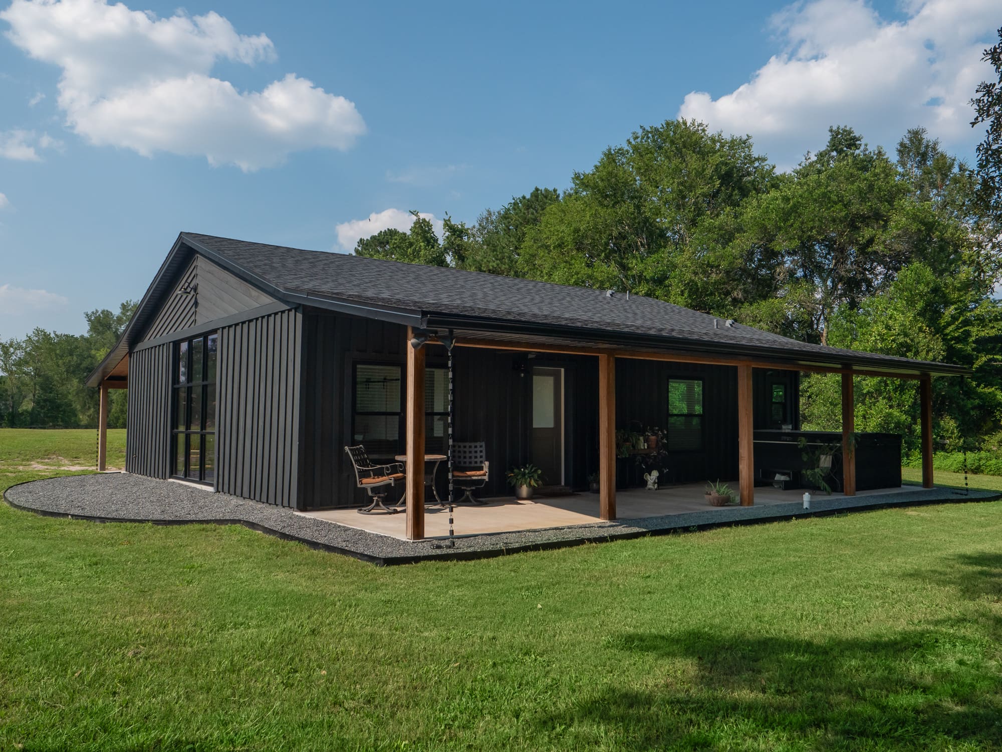 Modern black ADU with wood accents, covered porch, and gravel landscaping - Ways to Maximize Space - Robinson Renovations - Gainesville Fl Design Build Remodeler and Custom Home Builder