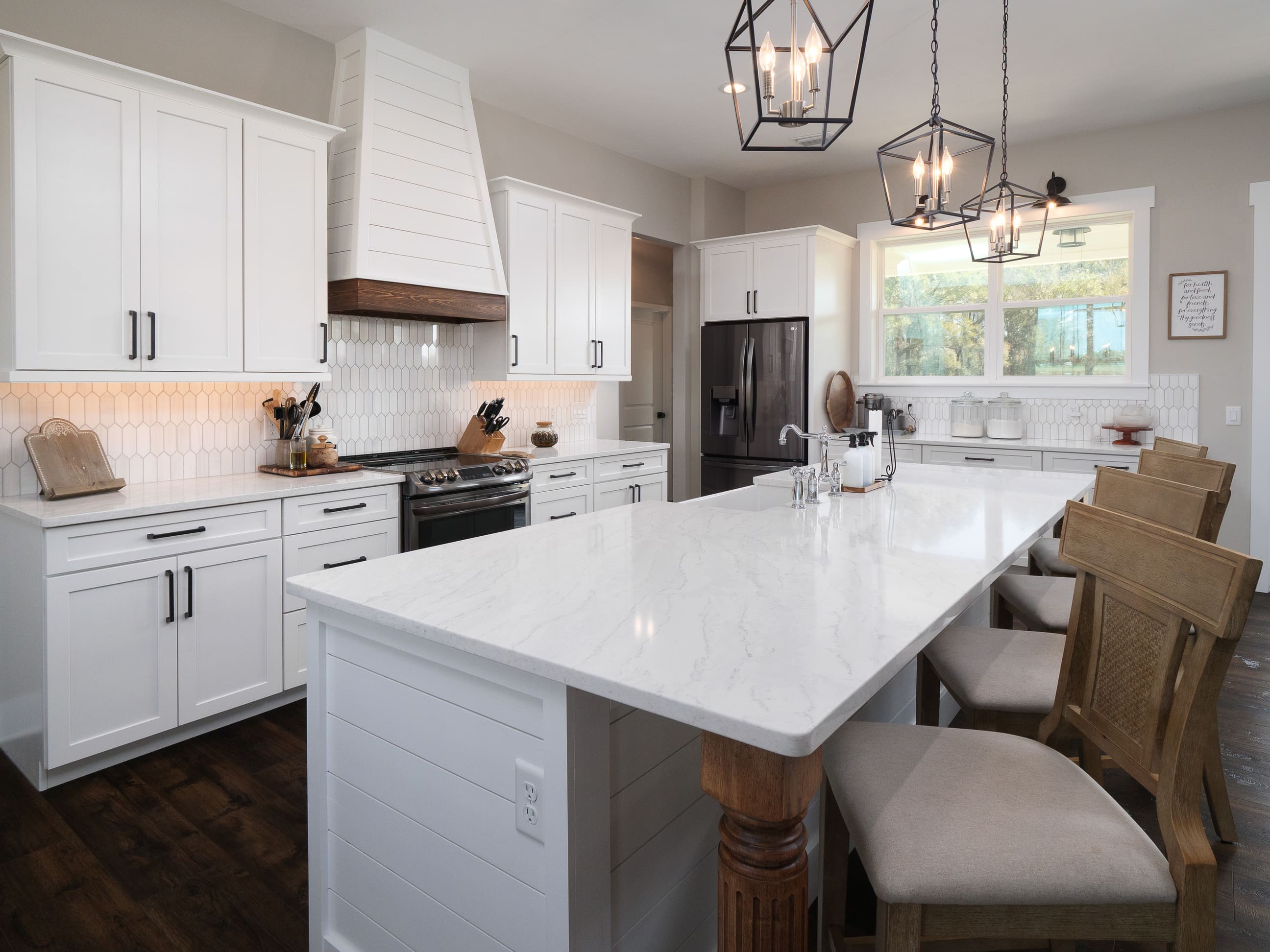 Bright kitchen featuring a large marble island, white shaker cabinets, and elegant pendant lighting - Timeless Custom Home Design Trends in Gainesville, Florida - Robinson Renovations - Custom Home Builder